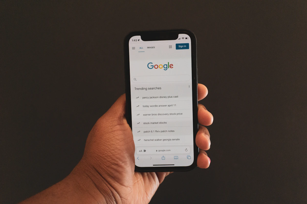 A hand holding a phone displaying a Google search